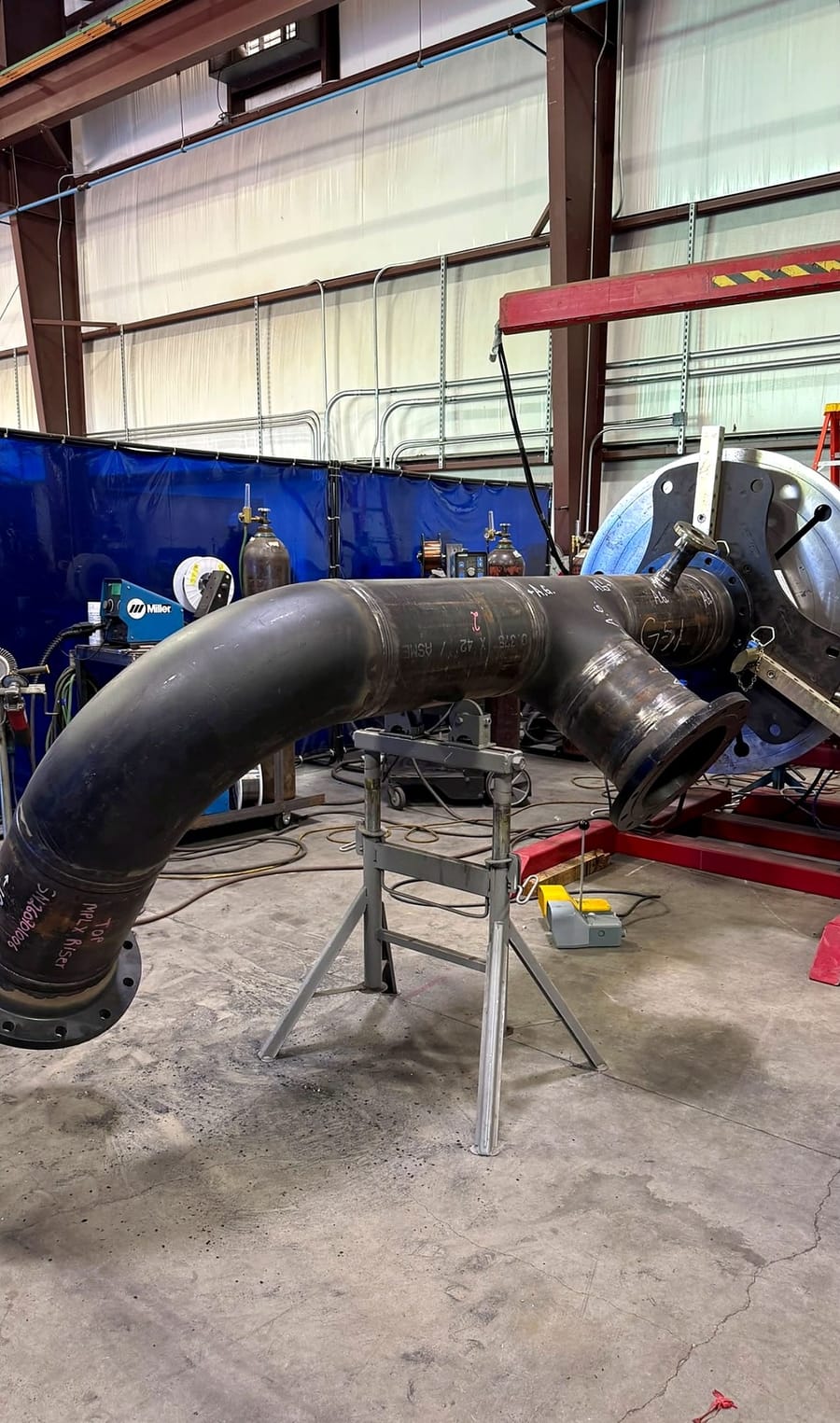 A welded pipe spool with a formed bend, set up on stands in the shop.