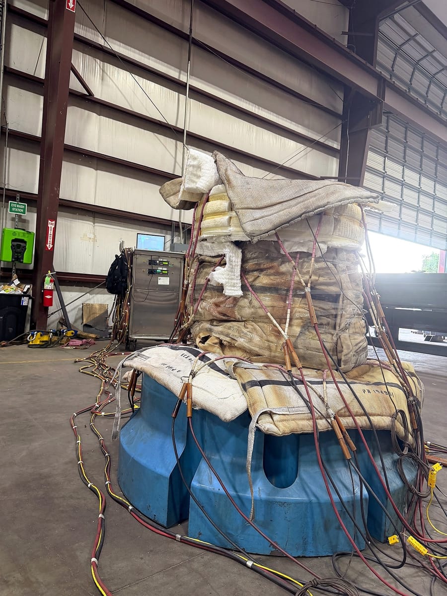 A large body under heat treatment blankets, thermocouple leads gathered at the base.