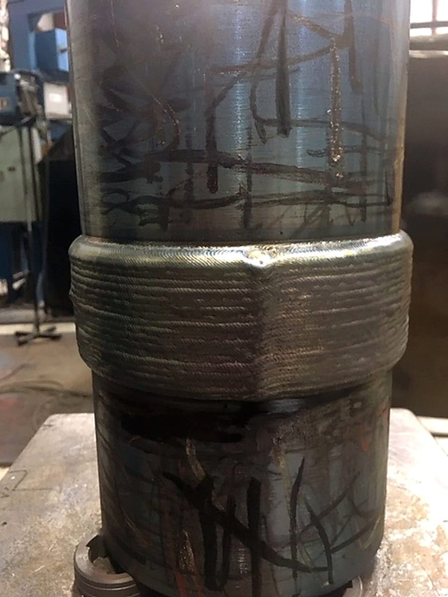 A circumferential weld build-up on a shaft, laid bead over bead.